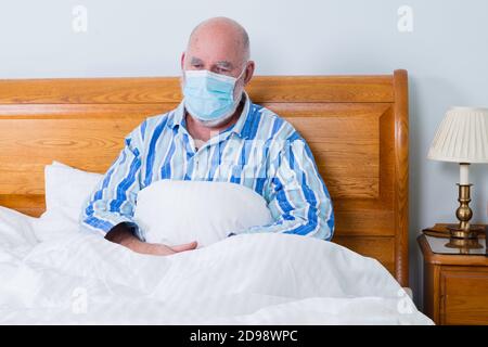 Homme âgé au lit, réfléchi et déprimé, portant un masque facial. Banque D'Images
