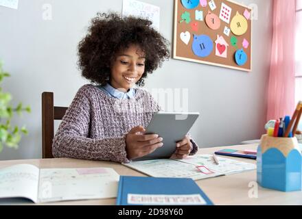 Jeune fille afro-américaine souriante tenant une tablette numérique à la maison. Banque D'Images