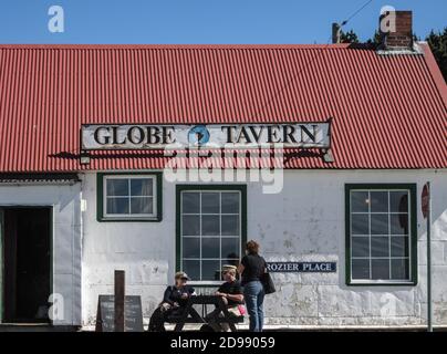 Stanley, îles Falkland, Royaume-Uni - 15 décembre 2008 : gros plan de l'entrée de Globe Tavern en tant que bâtiment blanc avec toit rouge sous ciel bleu avec des gens Banque D'Images