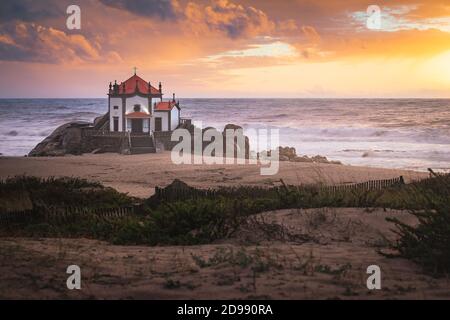 Coucher de soleil sur la plage avec une église sur la plage (Église de Senhor da Pedra) Banque D'Images