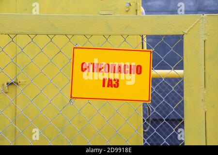 Une plaque jaune qui lit « gaz d'incendie » sur une clôture faite de mailles métalliques contenant des équipements à gaz. Le concept d'approvisionnement en gaz, de sécurité, de danger et de sécurité. Banque D'Images