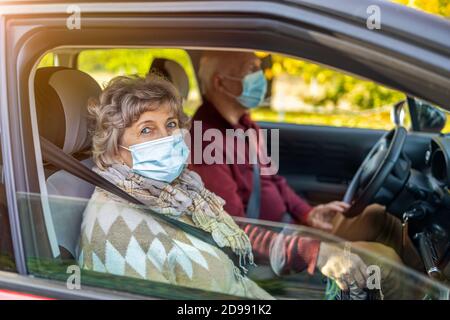 Couple senior portant des masques de protection dans leur voiture Banque D'Images