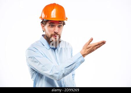 Un homme dans une industrie de construction de chemise de casque orange a travaillé arrière-plan clair Banque D'Images