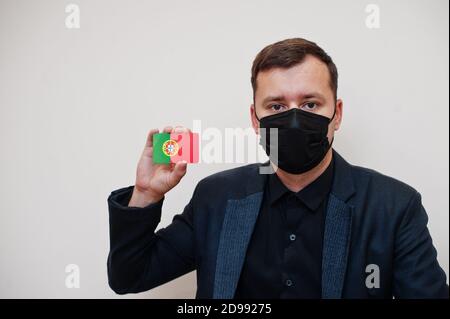 L'homme européen porte un masque classique noir et protège le visage, tenir la carte drapeau Portugal isolée sur fond blanc. Europe coronavirus Covid pays concept. Banque D'Images