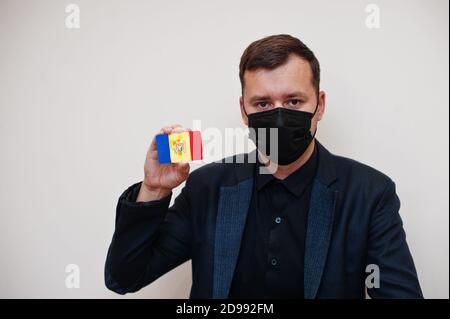 L'homme européen porte un masque classique noir et protège le visage, tenir la carte drapeau de Moldavie isolée sur fond blanc. Europe coronavirus Covid pays concept. Banque D'Images