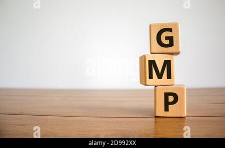 Cubes de bois avec le mot « GMP, bonne pratique de fabrication » sur une belle table en bois, fond blanc, espace de copie. Concept d'entreprise. Banque D'Images