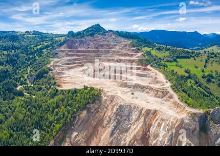 Terrasses dans la carrière d'extraction de ciment, les camions travaillent sur le site, vue aérienne Banque D'Images