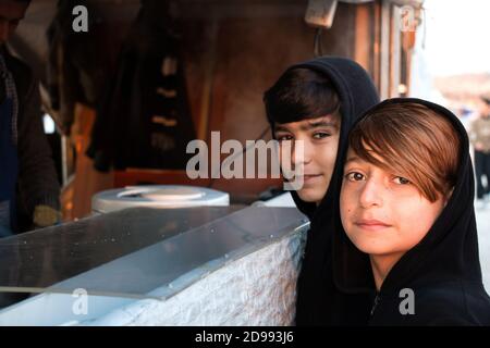 Les enfants posent pour une photographie ardemment sans savoir ce que l'avenir réserve. Skaramagas accueille un camp de réfugiés « temporaire », une sorte de salle d'attente où les migrants venant principalement de Syrie, d'Irak et d'Afghanistan restent avant d'être réinstallés ailleurs en Europe. À Skaramagas, ils peuvent également savoir si leur demande de réinstallation a été approuvée ou rejetée. Makariou, Skaramagkas, Grèce. Banque D'Images