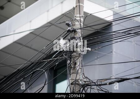 Beaucoup de câbles Internet et TV non organisés sur un poteau en béton à Bucarest. Banque D'Images