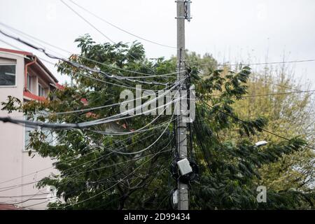 Beaucoup de câbles Internet et TV non organisés sur un poteau en béton à Bucarest. Banque D'Images