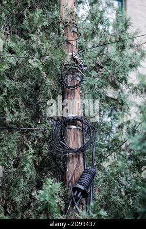 Beaucoup de câbles Internet et TV mal organisés sur un poteau en bois à Bucarest. Banque D'Images