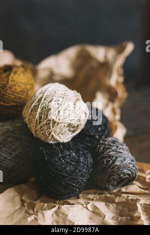 Balles de fil confortables pour tricoter à la main avec une feuille de chêne sèche sur un fond sombre. Fond d'automne pour la maison artisanale et lente. Mise au point sélective. Banque D'Images