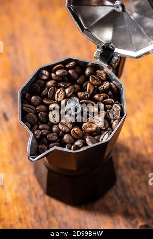 Grains de café rôtis dans un pot de moka sur une table en bois. Banque D'Images