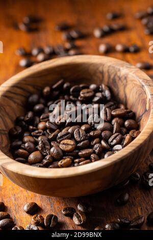 Grains de café rôtis dans un bol en bois sur une table en bois. Banque D'Images