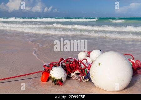 Des flotteurs blancs et des cordes rouges se posent sur la côte de sable humide Banque D'Images