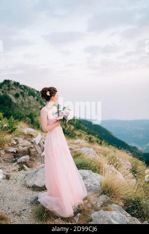 belle mariée et debout sur la montagne et tenant le bouquet Banque D'Images