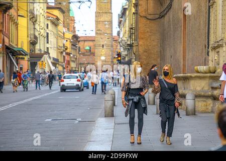 Bologne, Italie - 9 mai 2020: Phase 2 style de vie personnes avec les masques chirurgicaux dans la via Ugo Bassi route avec deux tours sur le fond. Coronavirus Banque D'Images