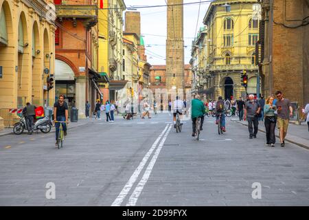 Bologna, Italie - 9 mai 2020: Les Italiens et les familles avec les masques chirurgicaux marchant et faisant du vélo sur la route avec deux tours sur le Banque D'Images