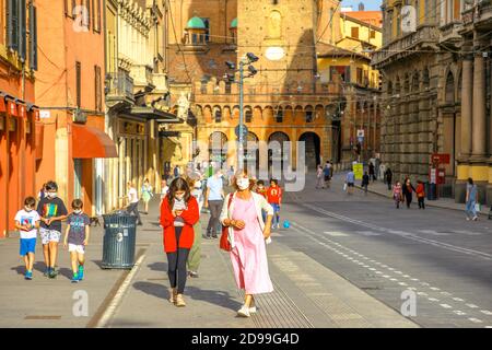 Bologne, Italie - 9 mai 2020: Familles italiennes avec les masques chirurgicaux marchant dans la rue via Rizzoli avec deux tours carrés. Covid-19 temps avec social Banque D'Images