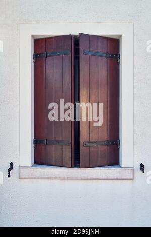 Fenêtre avec volets bruns sur le mur gris. Architecture colorée sur l'île de Burano, Venise, Italie. Banque D'Images