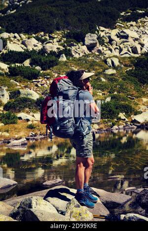 Femme debout sur les pierres et reposant sur la grenouille lac dans la montagne de Pirin photo verticale foyer sélectif Banque D'Images