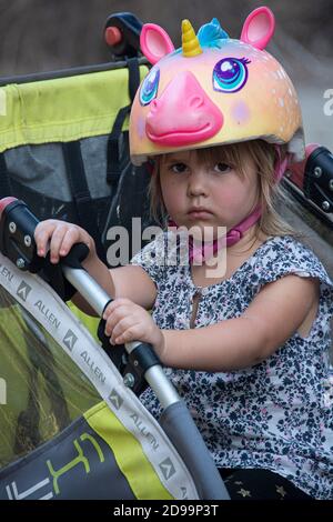 Une petite fille avec un casque unicorn ayant une mauvaise journée au parc. Banque D'Images