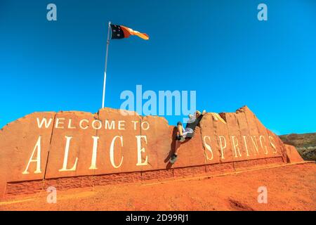 Happy Warinfree touriste woman at Alice Springs Welcome Sign in Northern Territory, Central Australia. Tourisme dans le désert de l'Outback Red Centre. Déplacement Banque D'Images