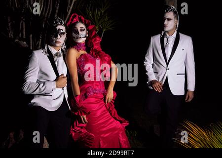 Une catrina et deux catrin portant des vêtements élégants dans un forêt sombre la nuit Banque D'Images