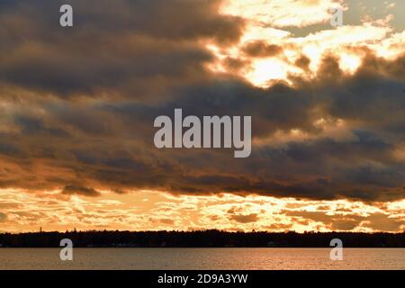 Trout Lake, Michigan, États-Unis. Les nuages qui se défrissent permettent au soleil de la fin de l'après-midi d'apparaître juste avant le coucher du soleil et projettent une réflexion sur la surface du lac. Banque D'Images