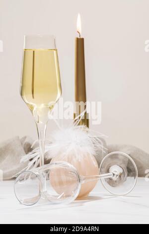 Une coupe de champagne à côté d'une boule de Noël et une coupe vide avec une bougie illuminée hors foyer à l'arrière. Concept de fête de Noël. Banque D'Images
