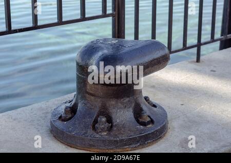 Grand bollard noir sur un quai en béton. Conçu pour la fixation et l'amarrage de gros navires, ferries, bateaux. Gros plan Banque D'Images