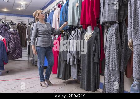 Une promenade de femme dans un grand magasin de vêtements pour femmes. Sélection de garde-robe pour l'été Banque D'Images