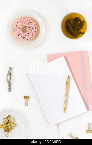 Repose-plat élégant pour blogueur de mode pour femme. Lieu de travail d'un travailleur indépendant ou de bureau: Un Bloc-notes avec une page vierge, un stylo, une tasse de thé vert, un Banque D'Images