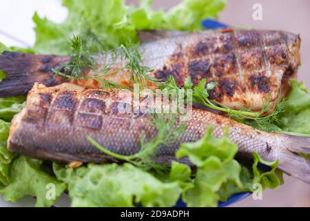 Poisson frit au bar sur un grill avec des légumes verts Banque D'Images