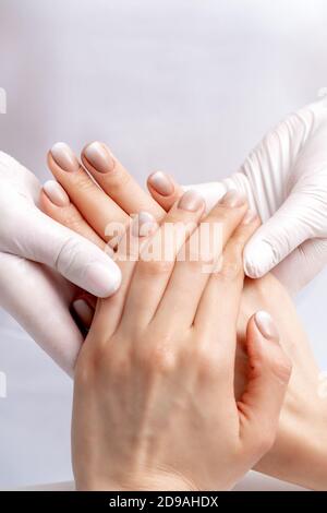 Manucuriste portant des gants faisant un massage de cire sur les mains des femmes avec manucure dans un salon de manucure Banque D'Images