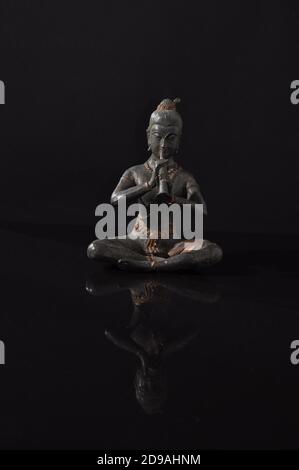 Statue de bouddha en bronze sur une surface réfléchissante noire avec une image miroir inversée. Banque D'Images