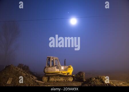 Excavatrice bleue travaillant la nuit dans la rue Banque D'Images