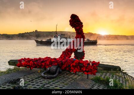 Appledore, North Devon, Angleterre. Mercredi 4 novembre 2020. Météo Royaume-Uni. Le navire de ravitaillement, MS Oldenburg, part pour l'île Lundy à l'aube froide et brumeuse, passant l'ancre du point de repère sur le quai d'Appledore, dans le nord du Devon. L'ancre a été recouverte de coquelicots tricotés à la main en préparation du jour du souvenir. Crédit : Terry Mathews/Alay Live News Banque D'Images