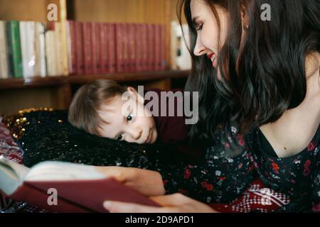 Une jeune femme lit un livre à un enfant. Une mère enseigne à son petit garçon à lire. Banque D'Images