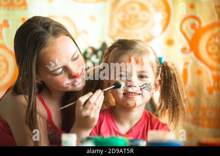 Les jeunes sœurs jouent volontiers à la maison avec la peinture. Banque D'Images