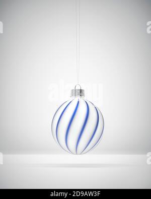 Boule de Noël blanc mat ornée de rayures bleues royales torsadées. Arrière-plan ombré blanc. Décoration de Noël, concept d'atmosphère festive. Banque D'Images