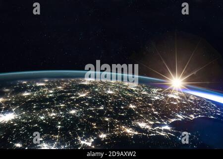 Image composite du soleil levant sur la terre vue de l'espace avec les lumières des villes illuminées la nuit. Activités humaines, gaz à effet de serre émissi Banque D'Images