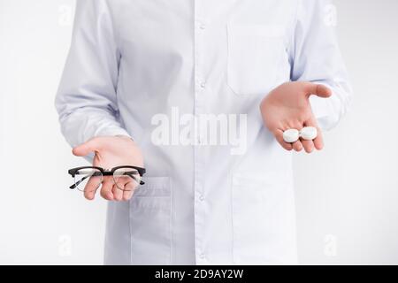 Vue rognée de l'ophtalmologiste tenant sur les paumes verres récipient plus haut que les lunettes isolées sur blanc Banque D'Images