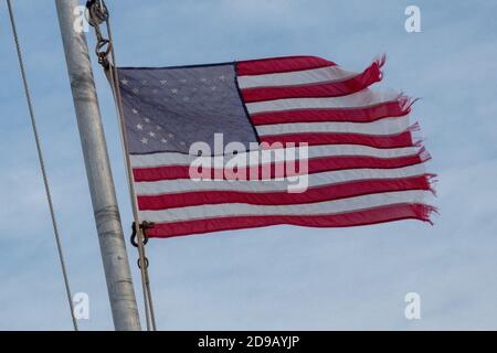 Vent en lambeaux et effiloché étoiles et bandes drapeau des États-Unis volant de la poupe d'un bateau touristique dans la baie de Skagit juste avant la tombée de la nuit de l'État de Washington. 02 août 2013. Photo: Neil Turner Banque D'Images