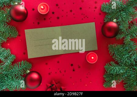 Carte de vœux de Noël avec espace pour le texte de félicitations, branches d'arbre de noël, bougies et décorations sur la surface rouge. Joyeux Noël heureux Banque D'Images