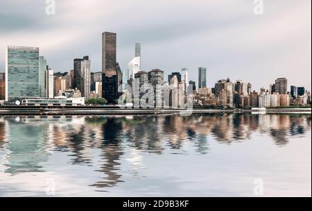 Manhattan, New York. Vue panoramique sur les gratte-ciel de Midtown sur l'East River lors d'une journée de réflexion sur l'eau Banque D'Images