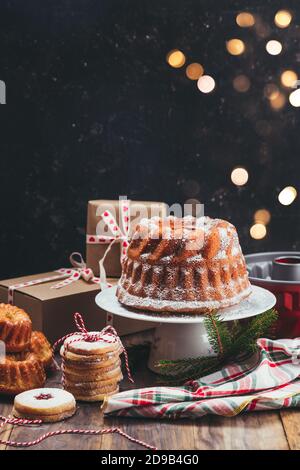 Assortiment de desserts de Noël faits maison et boîtes cadeaux sur un Table rustique en bois avec lumières de Noël Banque D'Images