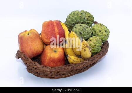 Pommes fraîches, bananes et pommes de crème anglaise gardées sur un panier en bois Banque D'Images