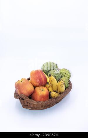 Pommes fraîches, bananes et pommes de crème anglaise gardées sur un panier en bois Banque D'Images