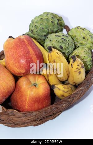 Pommes fraîches, bananes et pommes de crème anglaise gardées sur un panier en bois Banque D'Images